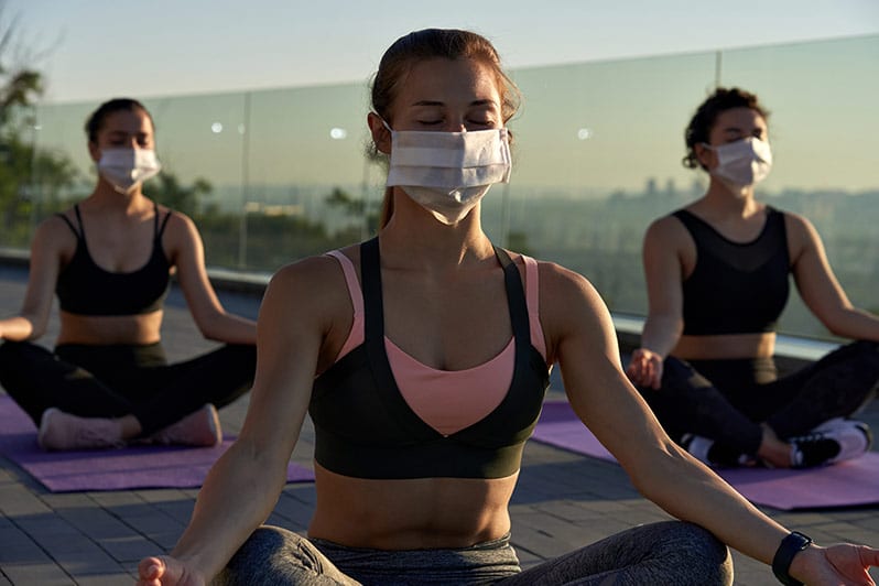 women wearing a mask and connecting with friends doing yoga