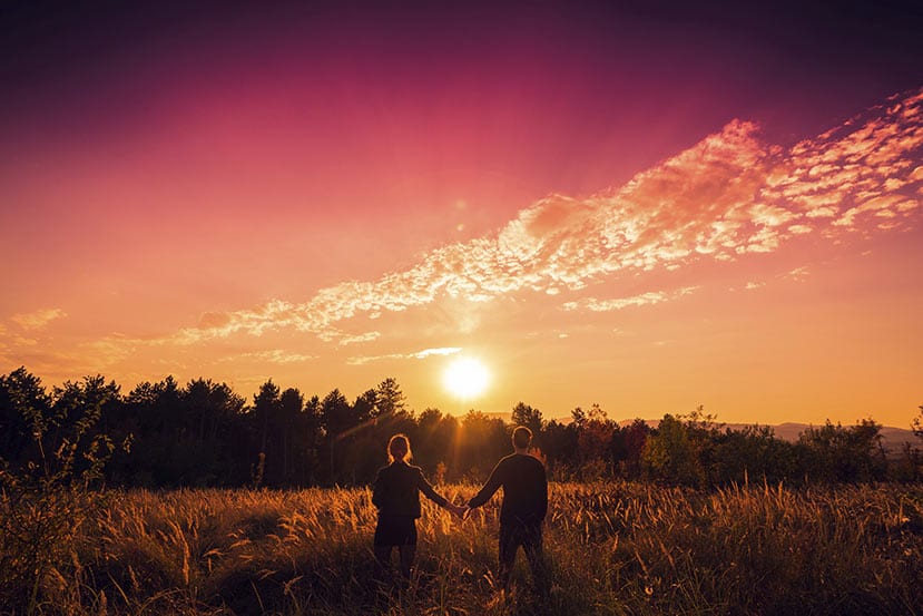 Twin flame soulmates holding hands in the sunset.