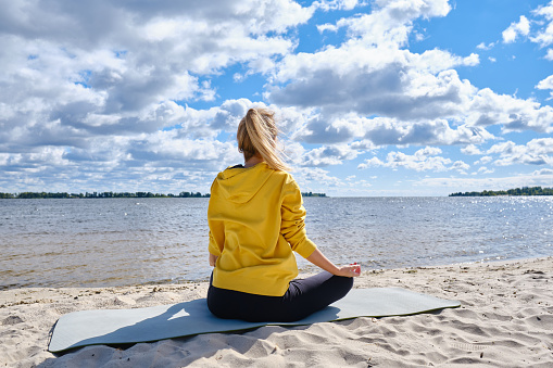 Woman sitting in meditation on beach