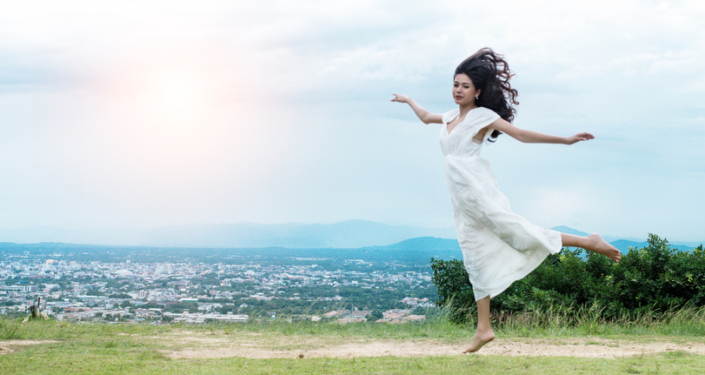 The beauty lady with white dress is dancing with bard feet,on ground floor,sky background.