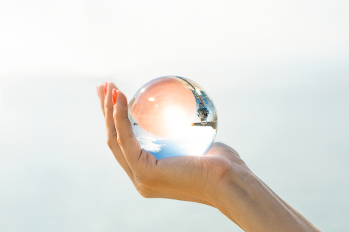 A female hand holds a glass ball new lens method